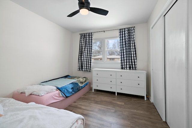 bedroom with dark hardwood / wood-style floors, ceiling fan, and a closet