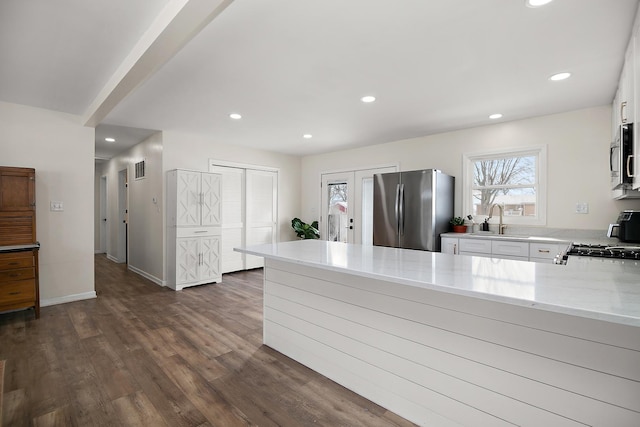 kitchen featuring sink, white cabinetry, stainless steel appliances, light stone countertops, and dark hardwood / wood-style flooring