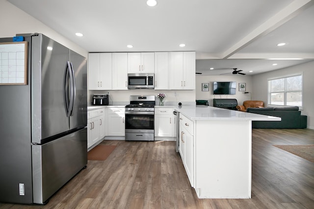 kitchen featuring ceiling fan, hardwood / wood-style floors, stainless steel appliances, white cabinets, and kitchen peninsula