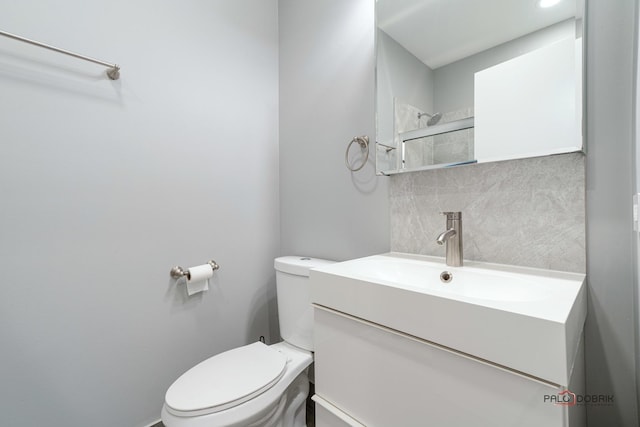 bathroom featuring vanity, toilet, and decorative backsplash