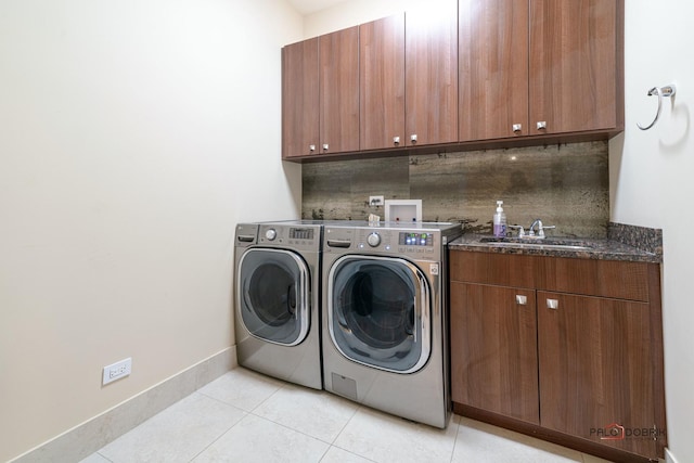 clothes washing area featuring sink, cabinets, washing machine and clothes dryer, and light tile patterned flooring