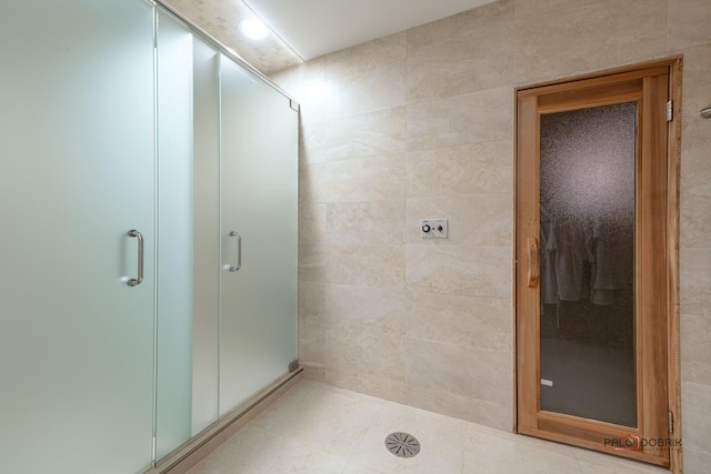 bathroom featuring tile walls, tile patterned flooring, and a shower with door