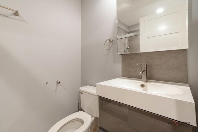 bathroom with vanity, toilet, an enclosed shower, and backsplash