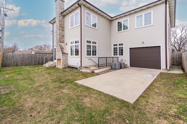 back of property with a yard, a garage, and central AC unit