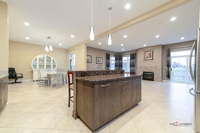 kitchen featuring dark stone counters, pendant lighting, dark brown cabinetry, and a spacious island