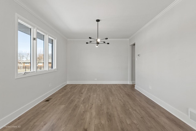 spare room with an inviting chandelier, crown molding, and light hardwood / wood-style floors