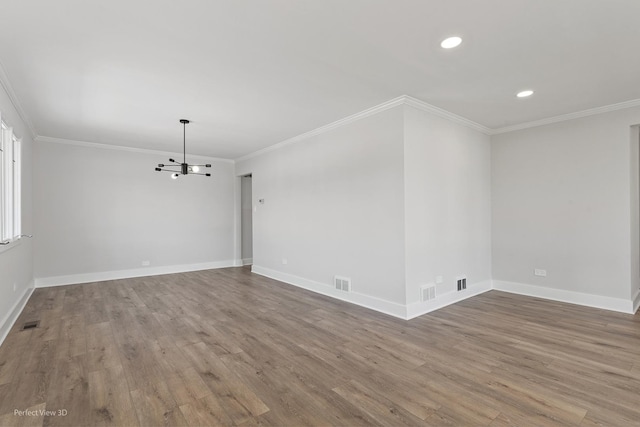 empty room with ornamental molding, wood-type flooring, and a notable chandelier