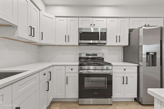 kitchen with white cabinetry, decorative backsplash, light hardwood / wood-style flooring, and stainless steel appliances