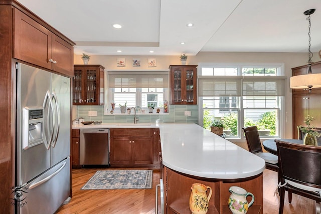 kitchen featuring sink, decorative light fixtures, a center island, light hardwood / wood-style flooring, and stainless steel appliances