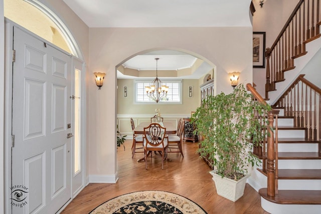 entrance foyer with hardwood / wood-style flooring, a chandelier, and a tray ceiling