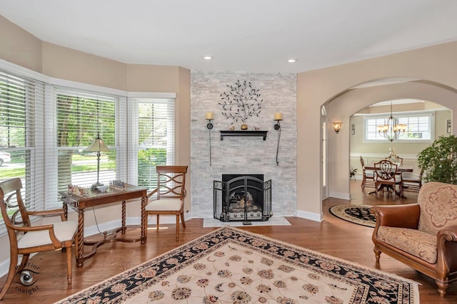 sitting room featuring an inviting chandelier, wood-type flooring, and a fireplace