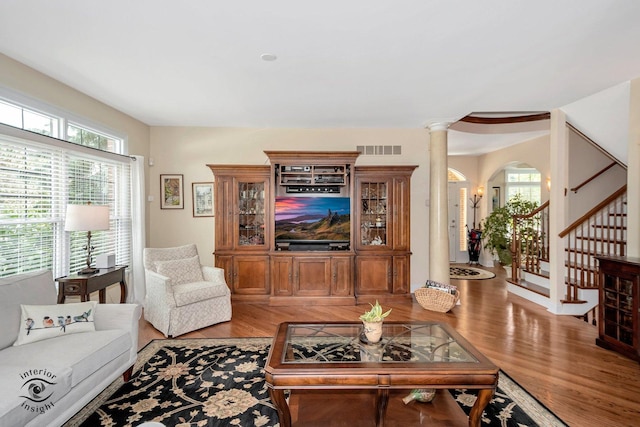 living room featuring decorative columns, plenty of natural light, and hardwood / wood-style floors