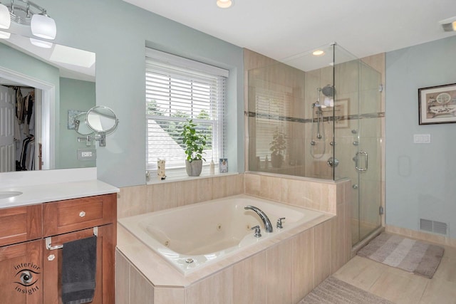 bathroom featuring independent shower and bath, vanity, tile patterned floors, and a skylight