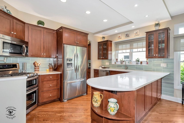 kitchen with stainless steel appliances, sink, light hardwood / wood-style floors, and decorative backsplash