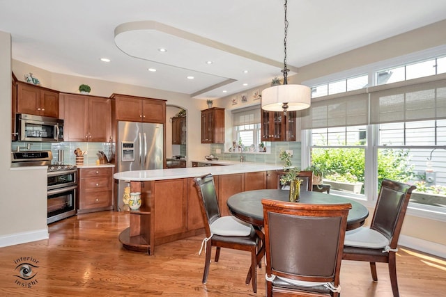 kitchen with wood-type flooring, appliances with stainless steel finishes, decorative backsplash, and decorative light fixtures