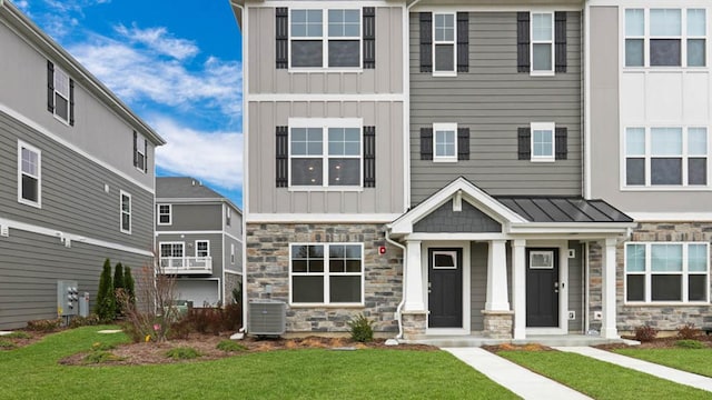 view of front of home with central AC unit and a front yard