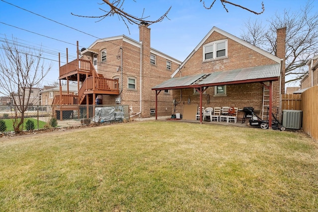 rear view of house featuring a wooden deck, a lawn, and central air condition unit