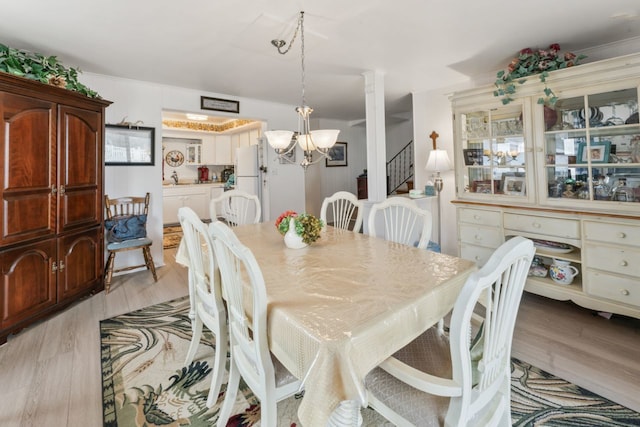 dining room with a chandelier, stairway, and light wood-style flooring