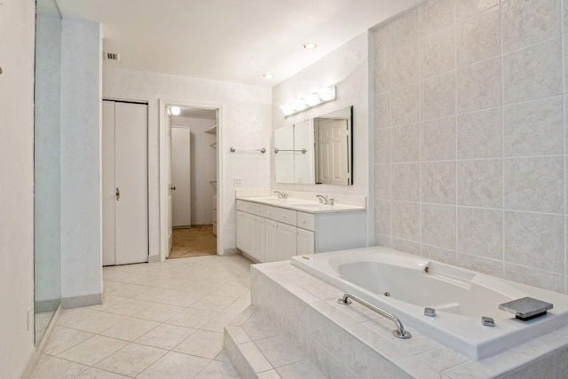 bathroom with tile patterned floors, visible vents, a tub with jets, baseboards, and vanity