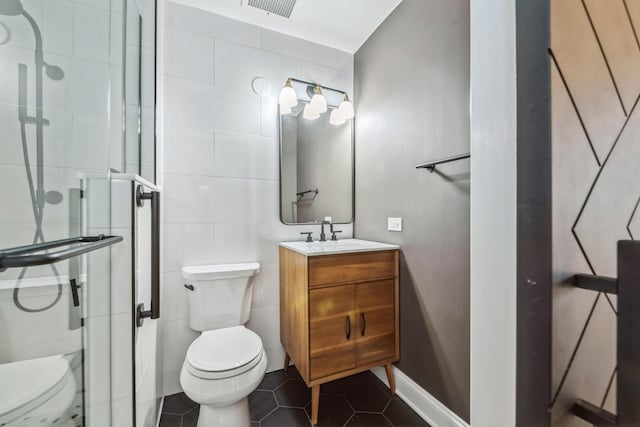 full bath featuring tile patterned floors, toilet, a stall shower, tile walls, and vanity