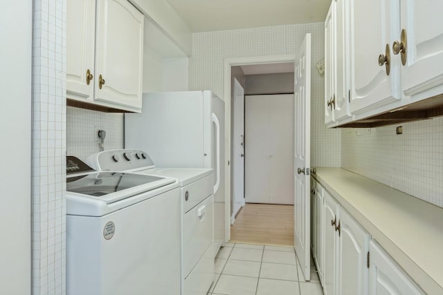 laundry room with light tile patterned floors, washing machine and dryer, and cabinet space