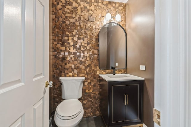 half bathroom featuring toilet, tile walls, and vanity