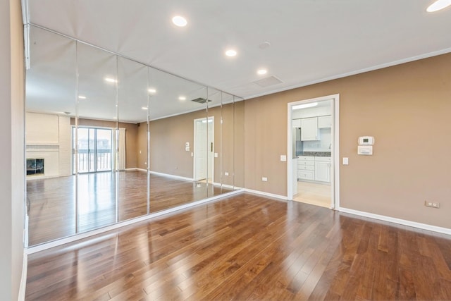 spare room with visible vents, wood finished floors, recessed lighting, a fireplace, and baseboards