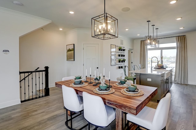 dining space with ornamental molding, sink, and light wood-type flooring