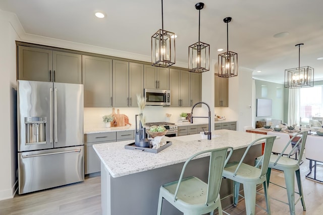 kitchen with sink, light stone counters, hanging light fixtures, ornamental molding, and stainless steel appliances