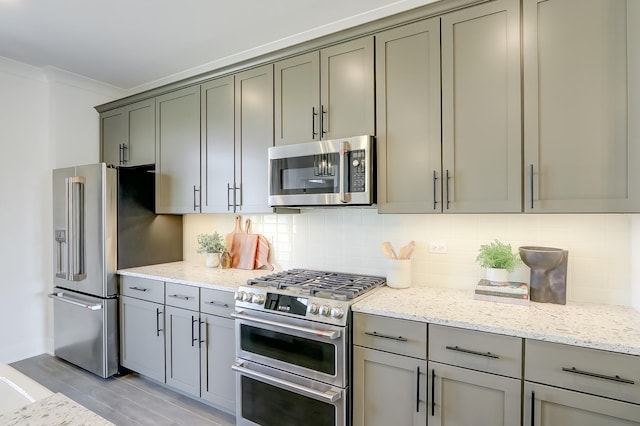 kitchen featuring tasteful backsplash, ornamental molding, appliances with stainless steel finishes, and light stone counters