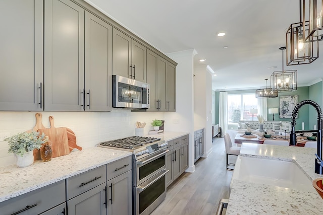 kitchen featuring appliances with stainless steel finishes, sink, decorative backsplash, ornamental molding, and light wood-type flooring