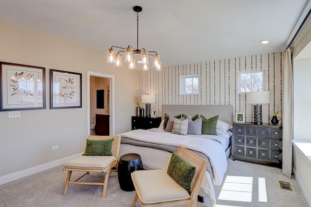 bedroom with light colored carpet, lofted ceiling, connected bathroom, and a chandelier