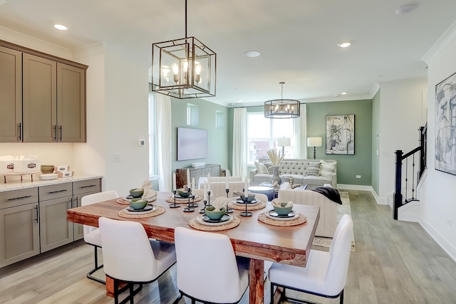 dining room with ornamental molding, an inviting chandelier, and light hardwood / wood-style flooring