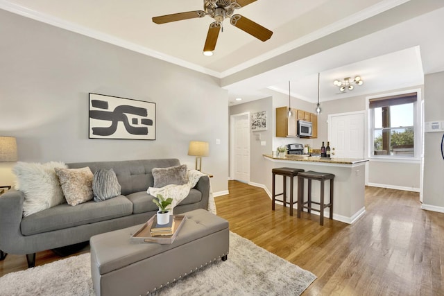 living room featuring crown molding, ceiling fan, and light wood-type flooring