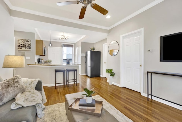 living room with wood-type flooring, ornamental molding, and ceiling fan