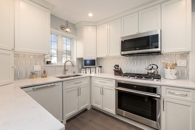 kitchen featuring appliances with stainless steel finishes, light stone countertops, sink, and white cabinets