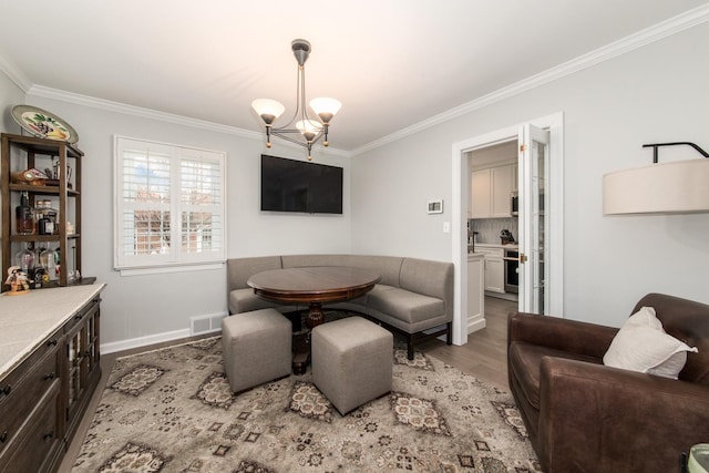 living room featuring hardwood / wood-style flooring, ornamental molding, and an inviting chandelier