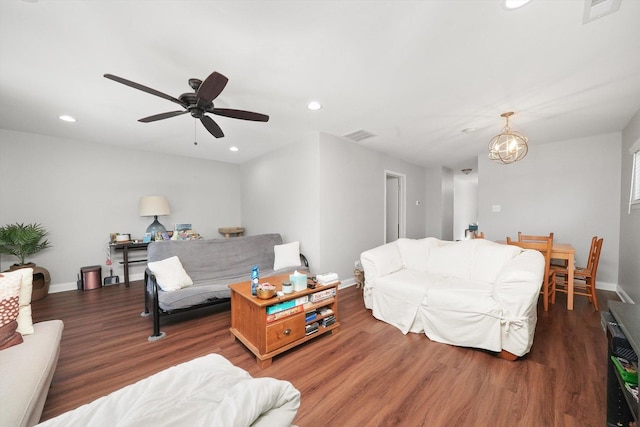 living room featuring ceiling fan with notable chandelier and dark hardwood / wood-style floors