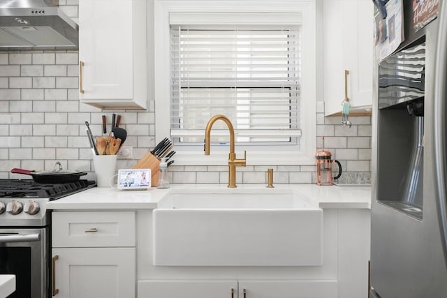 kitchen featuring sink, appliances with stainless steel finishes, light stone countertops, decorative backsplash, and white cabinets