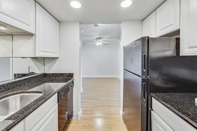 kitchen with white cabinetry, black appliances, light hardwood / wood-style flooring, and dark stone counters