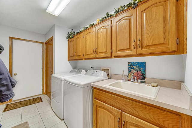 laundry room featuring sink, washing machine and dryer, cabinets, and light tile patterned flooring