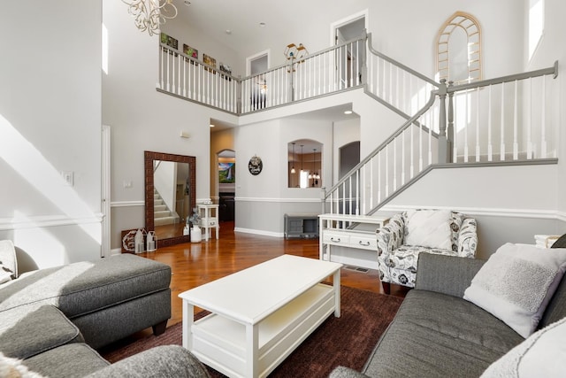 living room featuring a towering ceiling, dark hardwood / wood-style flooring, and a chandelier