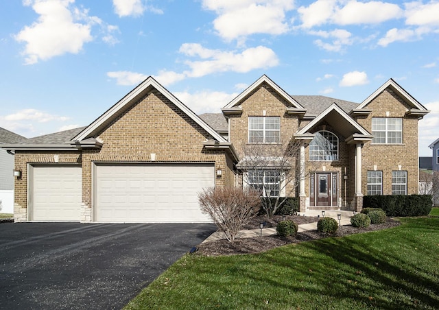 traditional home with aphalt driveway, brick siding, a shingled roof, an attached garage, and a front yard