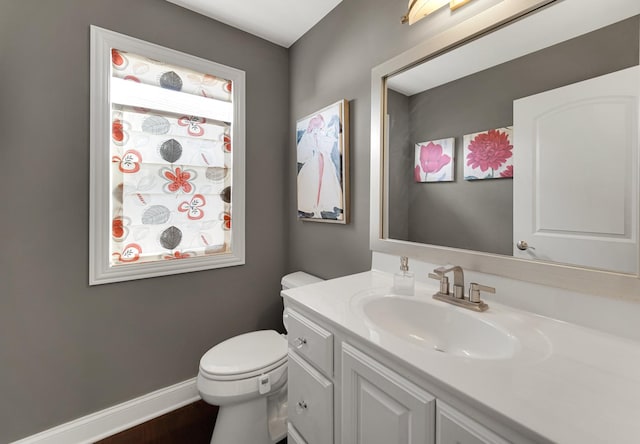 bathroom featuring toilet, vanity, and baseboards