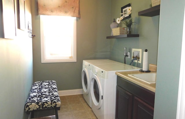 laundry area with washer and clothes dryer, cabinet space, light tile patterned flooring, a sink, and baseboards