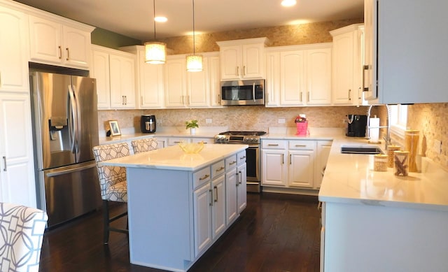 kitchen with appliances with stainless steel finishes, dark wood-style flooring, white cabinetry, and a center island