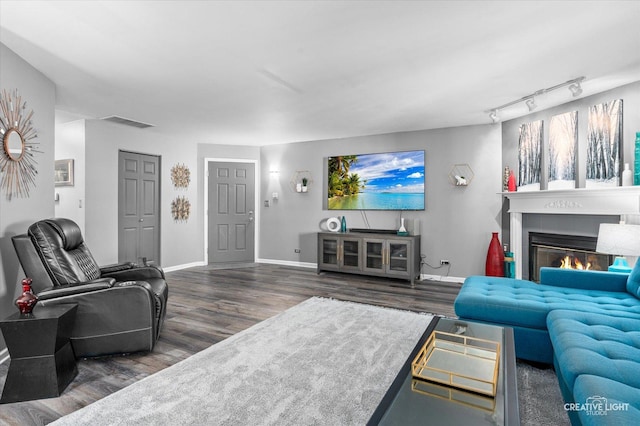 living room with dark hardwood / wood-style floors and track lighting