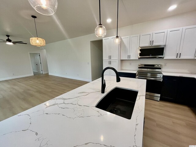 211 W Prairie St, Camp Point, IL 62320 - kitchen featuring a ceiling fan, a sink, stainless steel appliances, light wood-style floors, and decorative light fixtures