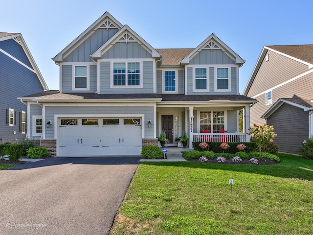 craftsman-style house featuring driveway, a front yard, board and batten siding, and brick siding