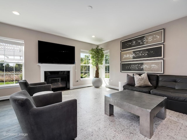 living room featuring a fireplace with flush hearth, baseboards, and recessed lighting